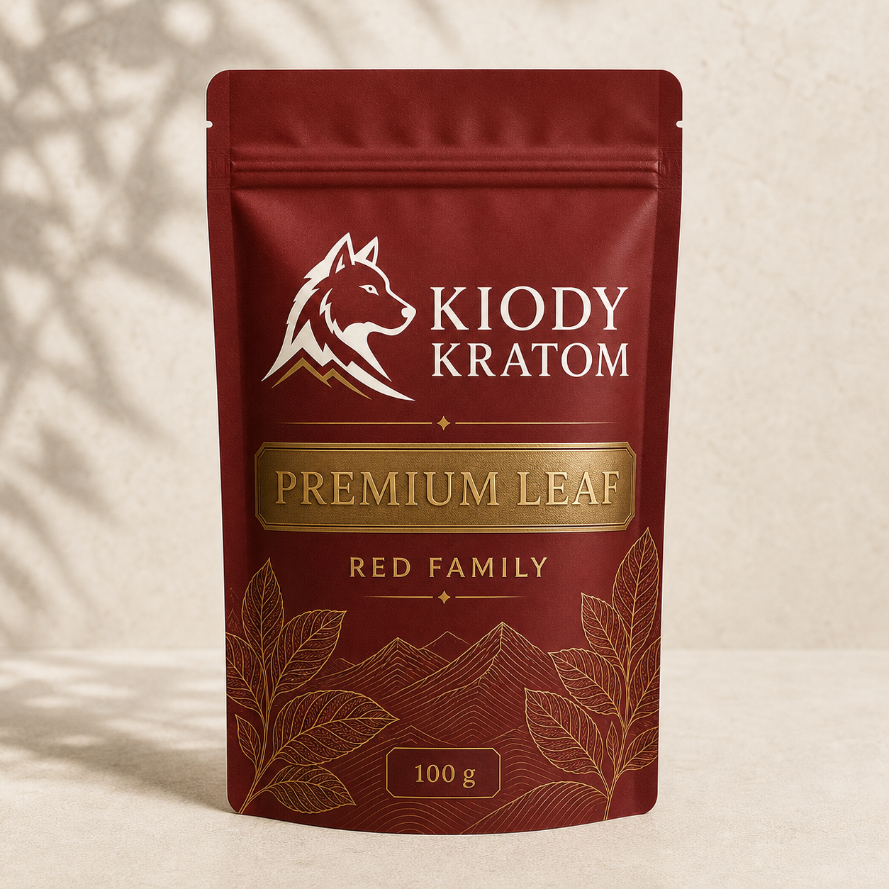 Kiody Red Family Premium Leaf kratom powder in a clay red 100 gram pouch with gold wolf, leaves, and mountain lines