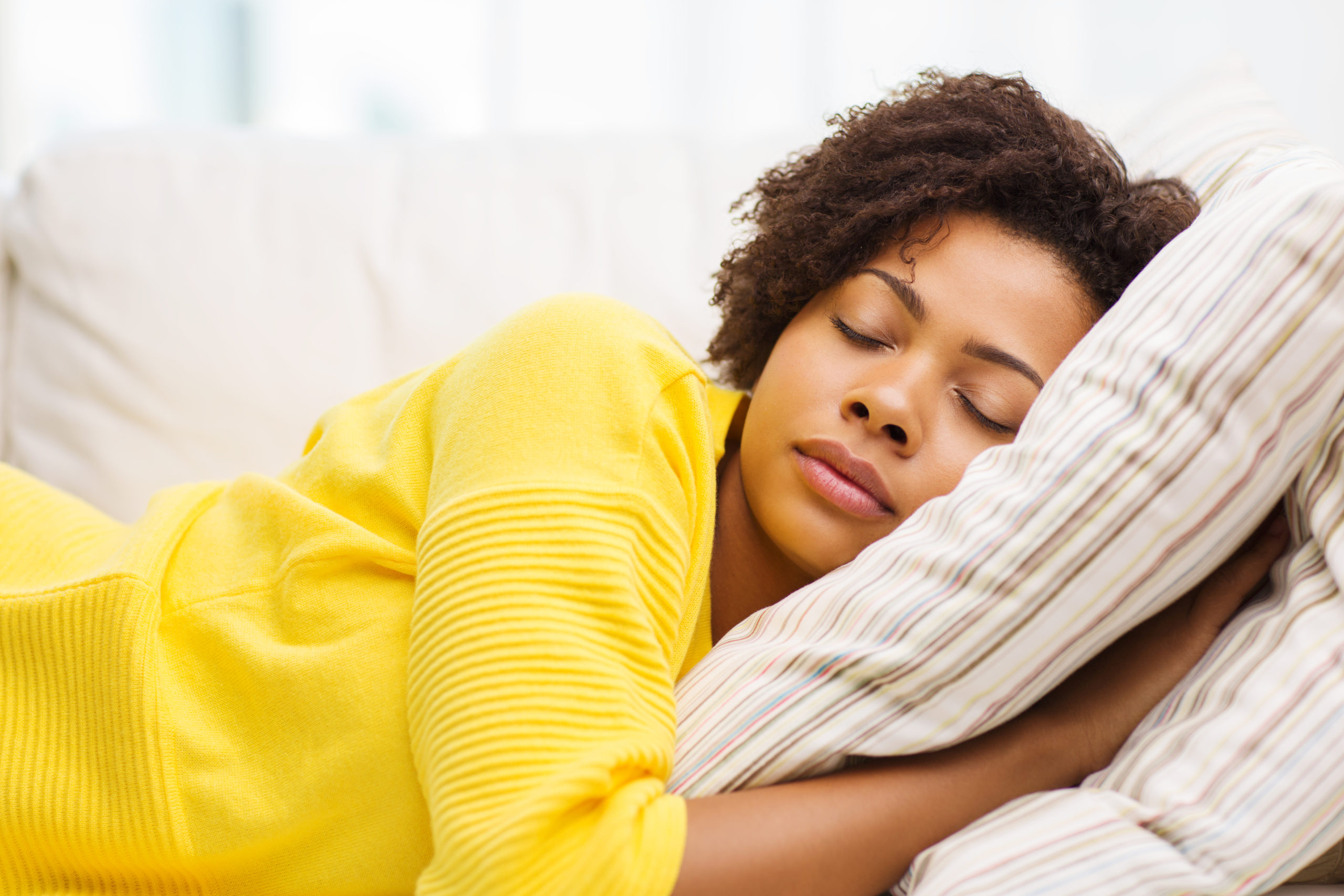 african american young woman sleeping on sofa at home